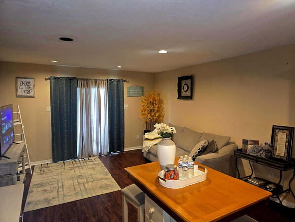 A living room with a wooden table, a sofa, a TV, and a decorative vase.