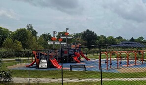 A playground with a slide, swings, and a fenced area.