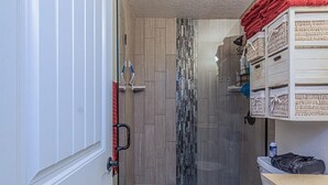 Un baño con cabina de ducha de vidrio, inodoro y toallero con toallas dobladas.