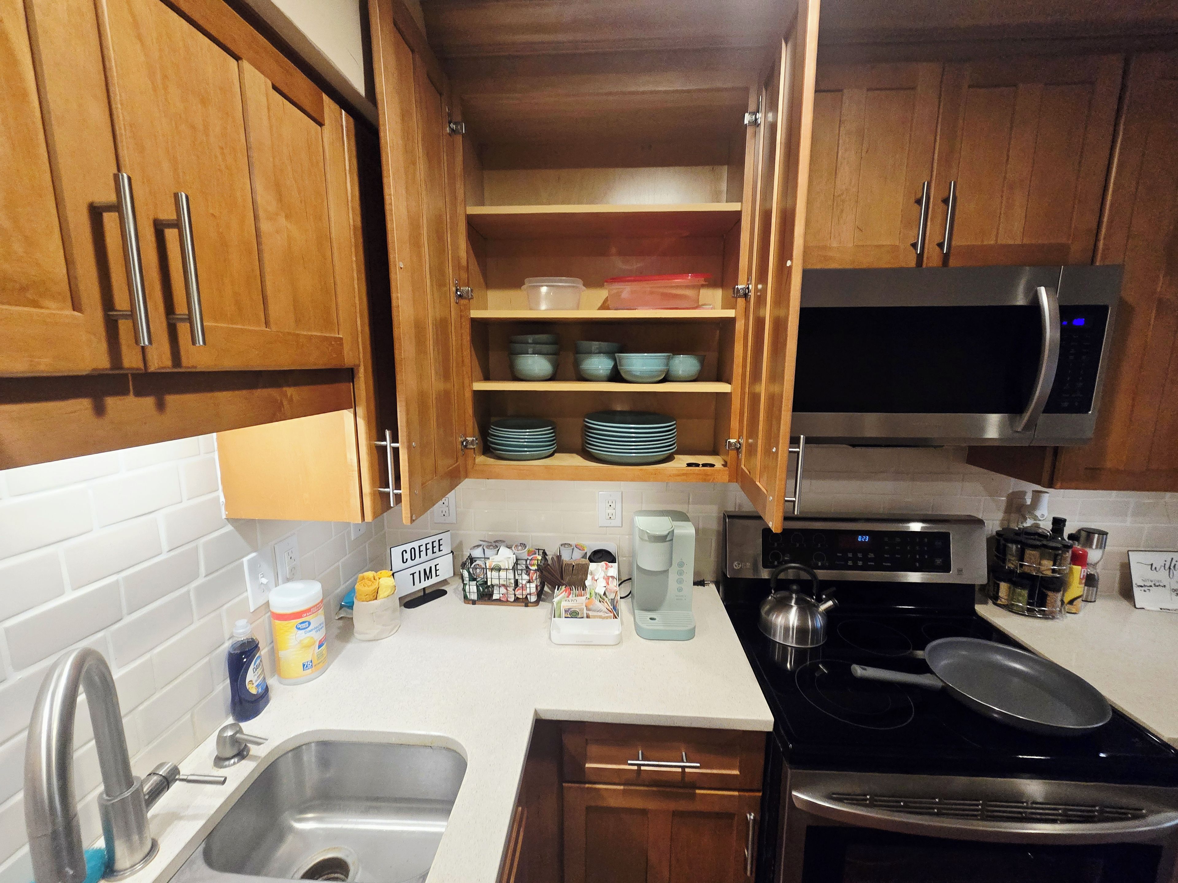 A kitchen with wooden cabinets, a stainless steel sink, a microwave, and a stove.
