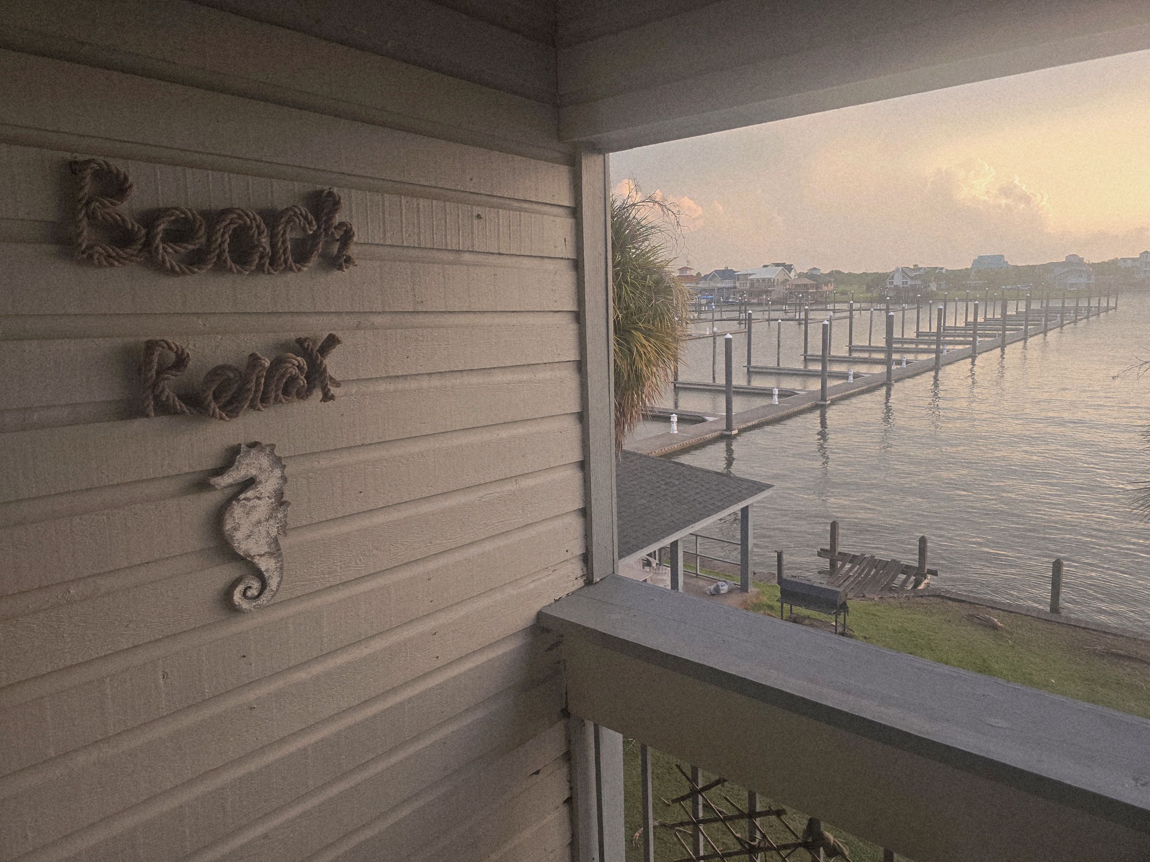 A view from a balcony overlooking a marina with a wooden railing and a seahorse decoration on the wall.