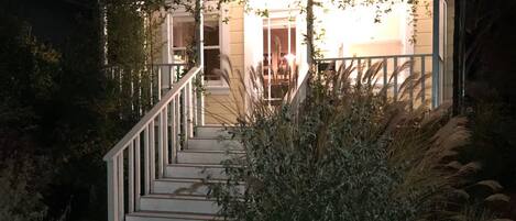 A house with a porch, a staircase leading to the entrance, and surrounding vegetation.