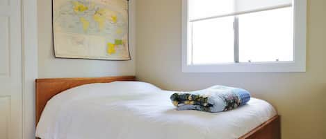 Une chambre avec un lit en bois, une grande fenêtre et une carte du monde accrochée au mur.