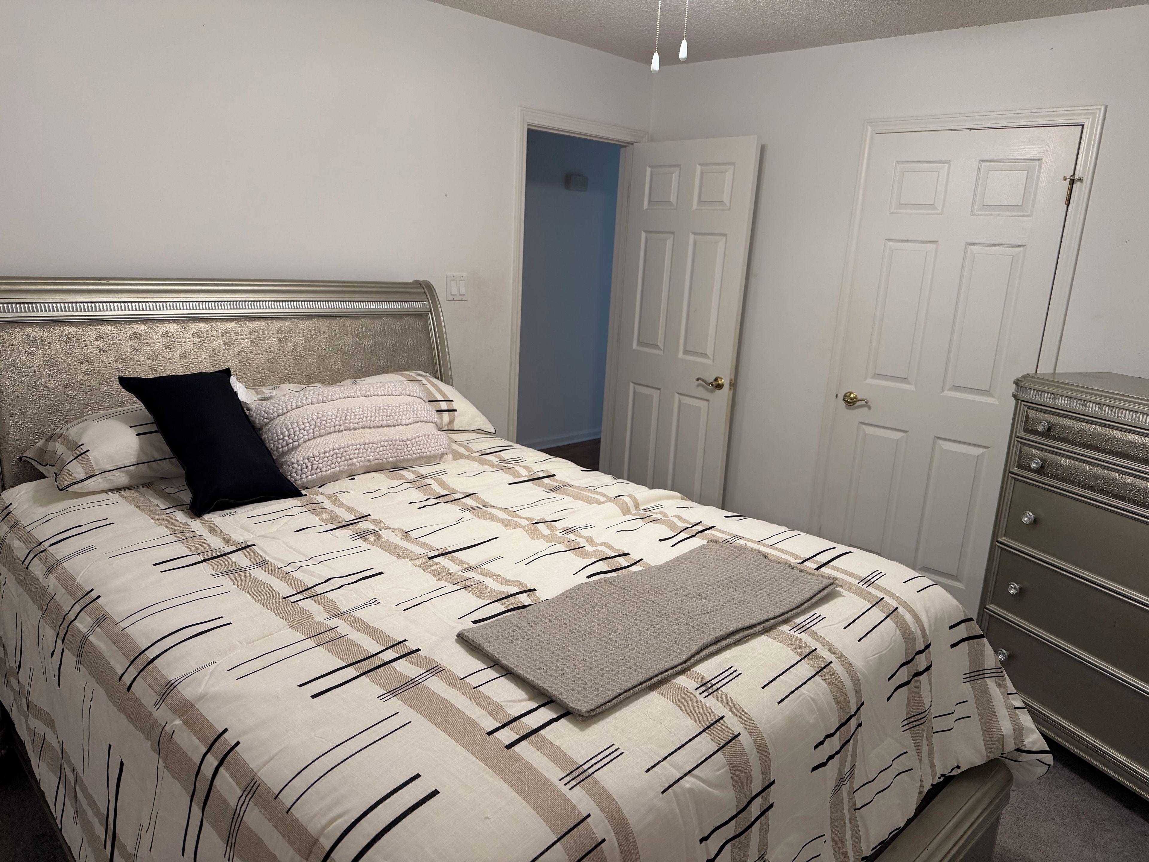 Une chambre à coucher avec un lit, une commode et une porte.