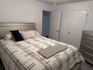 A bedroom with a bed, a dresser, and a door. - 3-bedroom house in superb Alexander with cool AC (Alexander)