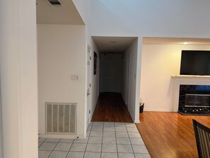A hallway with a tiled floor leading to a room with a fireplace and a television. - 3-bedroom house in superb Alexander with cool AC (Alexander)