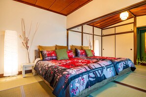 A traditional Japanese-style bedroom with tatami flooring, a low wooden bed frame, and a shoji screen door.