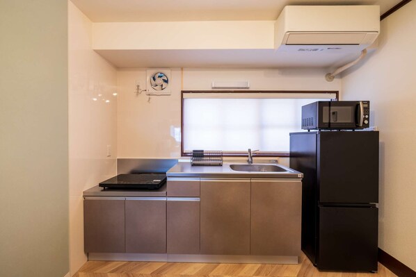 A compact kitchen with a built-in microwave, a sink, and a refrigerator.