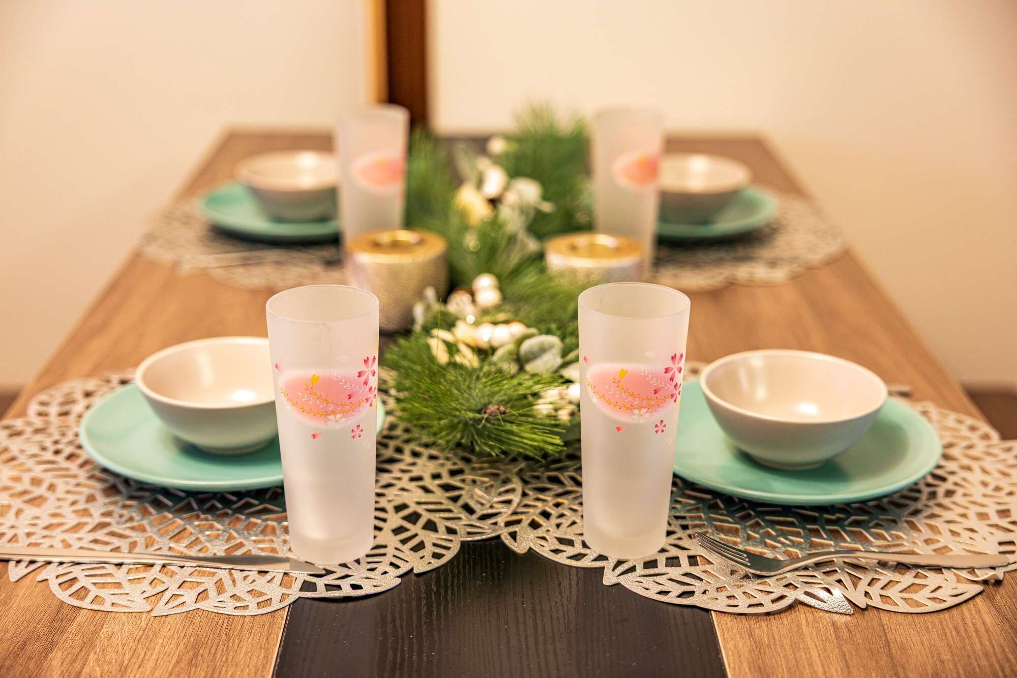 A table set with white glasses, teal plates, and a decorative doily.