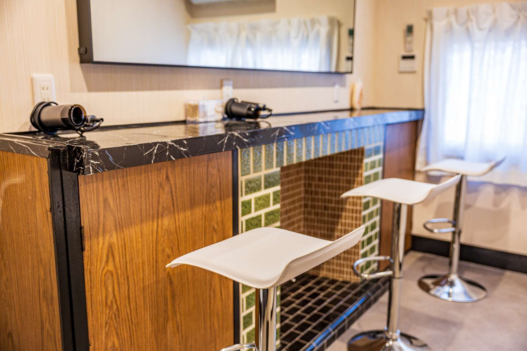 A bar area with a marble countertop, wooden paneling, and two white bar stools.