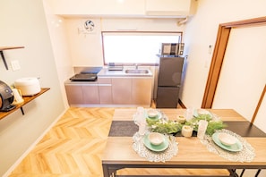 A compact kitchen with a microwave, stove, and refrigerator. - Traditional Japanese-Modern Private House in Nara｜147㎡｜Up to 16 Guests (奈良市)