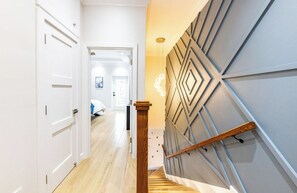 Eine Treppe mit hölzernem Geländer und einer Wand mit geometrischen Mustern.