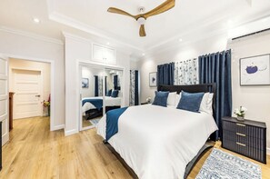 Ein Schlafzimmer mit einem großen Bett, einem Deckenventilator, einem Nachttisch und einem Spiegel.