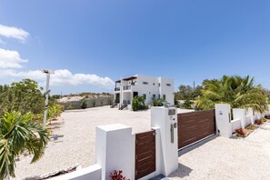 Ein modernes, zweistöckiges Gebäude mit weißer Fassade, einem verschlossenen Eingang und einem Schotterweg.