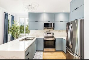 Une cuisine moderne dotée d’un îlot central, d’appareils électroménagers en acier inoxydable et de meubles de couleur bleu clair.