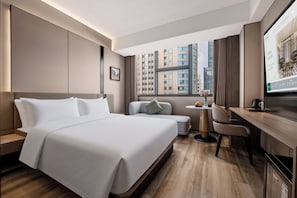 A hotel room with a large bed, a desk, a chair, and a view of the cityscape. - Madison Hotel (Guangzhou)