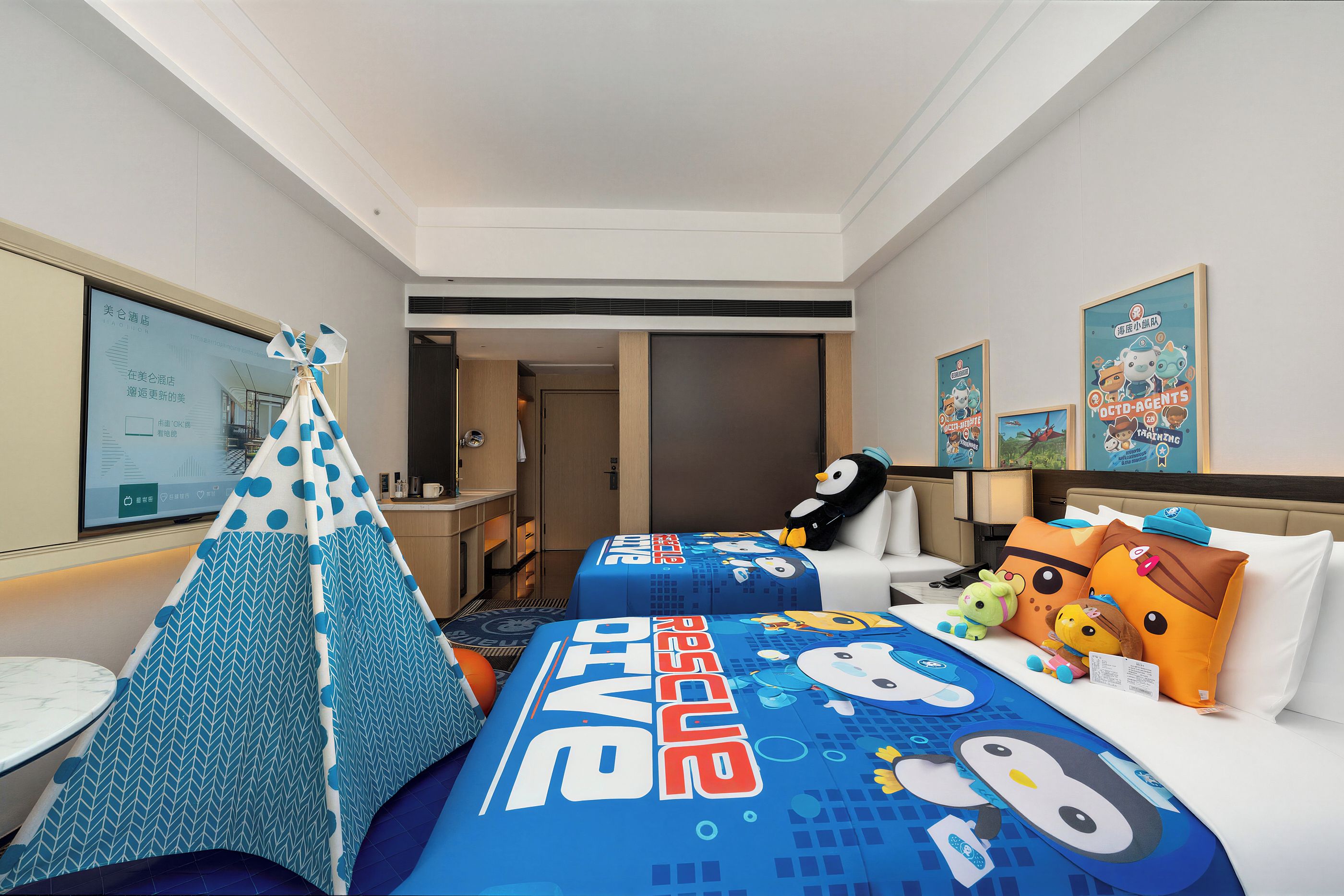 Ein Hotelzimmer mit einem 'Frozen'-Themenbett, einem kleinen Spielzelt und einem Kuscheltier-Pinguin.