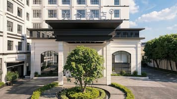 A hotel entrance with a modern design, featuring a central tree and a circular garden.