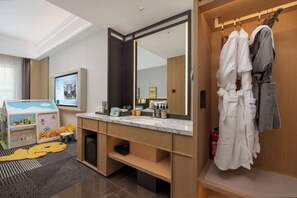 Un baño moderno con un espejo grande, tocador de madera y un perchero para bata.
