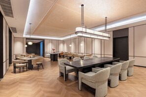 Un comedor moderno con una mesa larga y varias sillas, un techo con iluminación empotrada y una puerta visible.