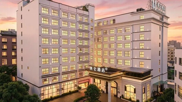 A multi-story hotel with a central entrance, surrounded by greenery and a water feature. - Madison Hotel (Guangzhou)