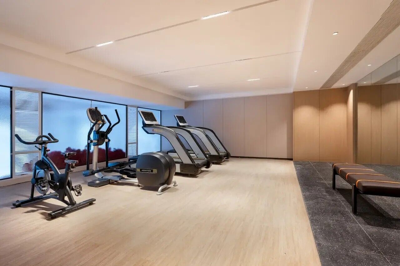 Un gimnasio con bicicletas estáticas, cintas de correr y un banco.