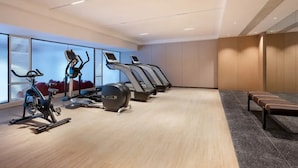 A gym with stationary bikes, treadmills, and a bench. - Madison Hotel (Guangzhou)