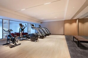 A gym with stationary bikes, treadmills, and a bench. - Madison Hotel (Guangzhou)