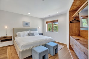 A modern bedroom with a large bed, bedside tables, a dresser, and a window with a view. - Casa Sereno - A Luxury Creekside Getaway w/ Panoramic Red Rock Views (Sedona)