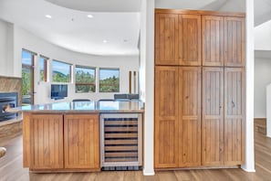 A modern kitchen with wooden cabinets, a built-in oven, and a large window overlooking a scenic landscape. - Casa Sereno - Luxury Creekside Escape • Heated Pool/Spa • Yoga Deck • Speakeasy (Sedona)