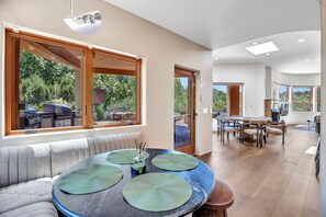 Ein modernes Interieur mit Essbereich, einer Couch und Blick ins Freie.