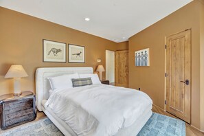 A bedroom with a bed, two wall-mounted lamps, a wooden wardrobe, and two framed pictures on the wall. - Casa Sereno - Luxury Creekside Escape • Heated Pool/Spa • Yoga Deck • Speakeasy (Sedona)