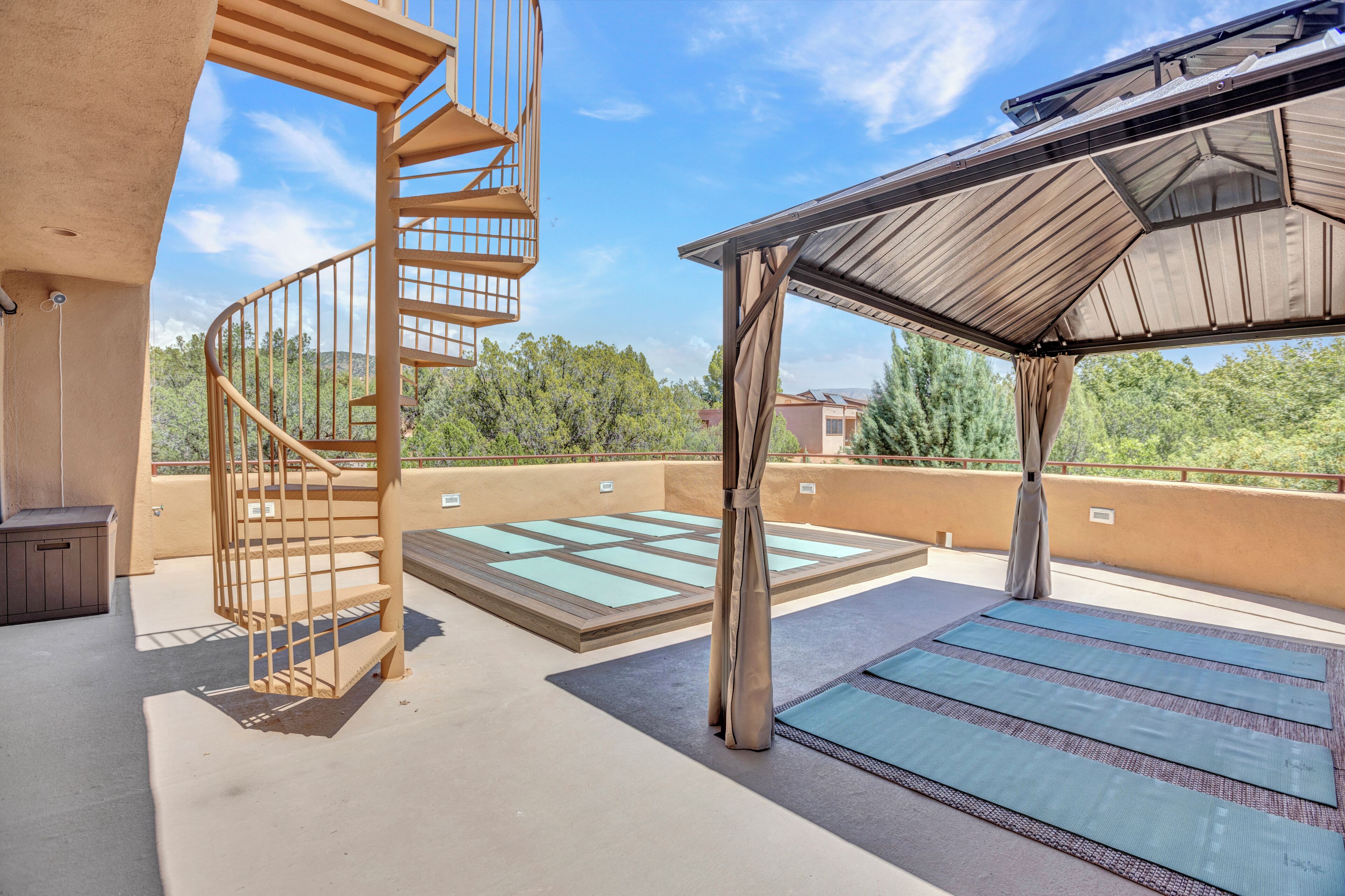 Una terrazza sul tetto con una scala a chiocciola, una zona salotto coperta e tappetini da yoga.
