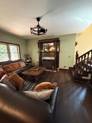 A living room with a fireplace, a staircase, and a large window.