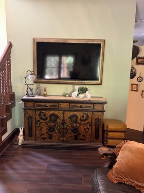 A room with a wooden cabinet, a television mounted on the wall, and a staircase.