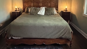A bedroom with a wooden bed, two bedside tables, a nightstand, a window, and a wall-mounted shelf.