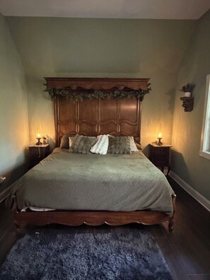 A bedroom with a wooden bed, two bedside tables, a nightstand, a window, and a wall-mounted shelf.
