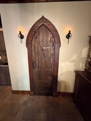 A wooden door with a metal latch and two wall-mounted light fixtures on either side.