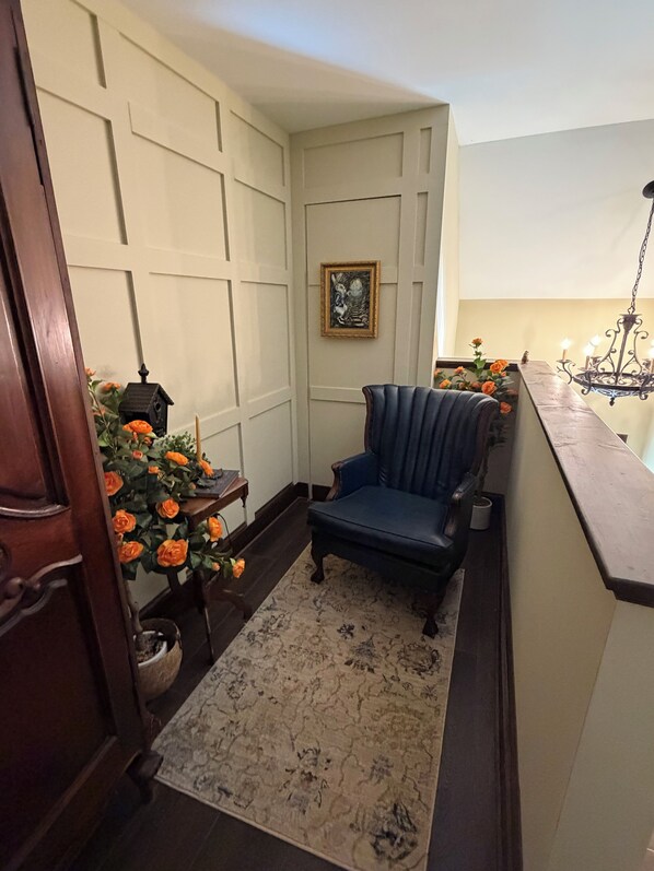 A corner room with a blue armchair, a small table with a lantern, and a potted plant with orange flowers.