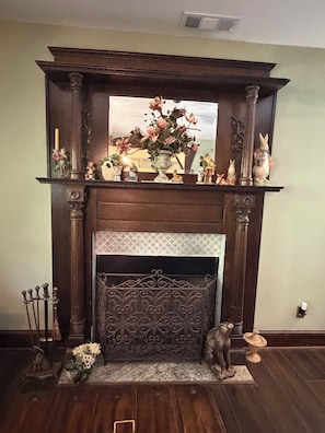 A fireplace with a mantel decorated with figurines and a vase of flowers.