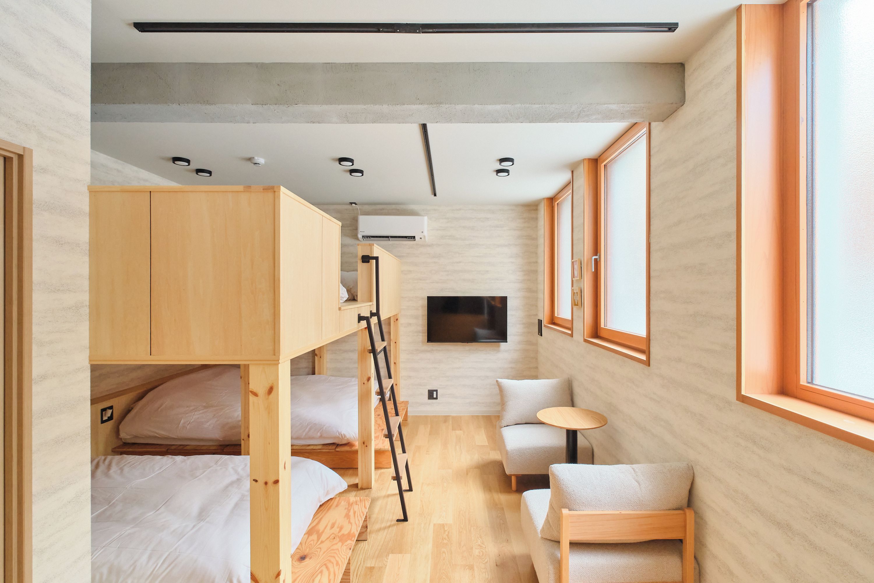 A compact room with bunk beds, a flat-screen TV, a small table, and a window.