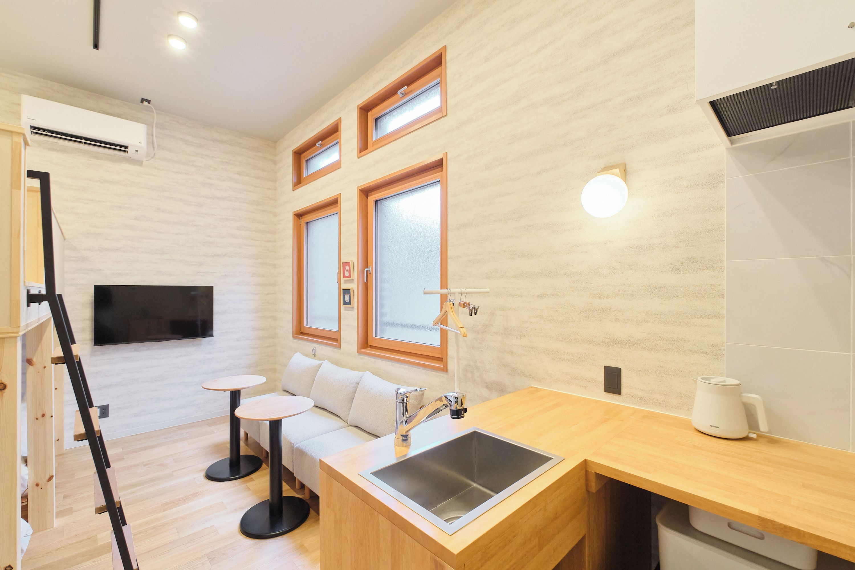 A compact kitchen with a built-in sink, a small round table, and a sofa.