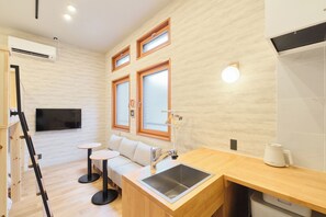 A compact kitchen with a built-in sink, a small round table, and a sofa. - Tomori (Tokyo)