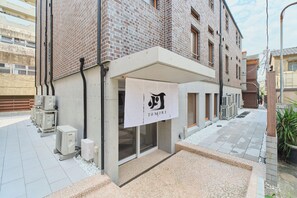 A building with a brick facade, a sign with a logo, and outdoor air conditioning units. - Tomori (Tokyo)