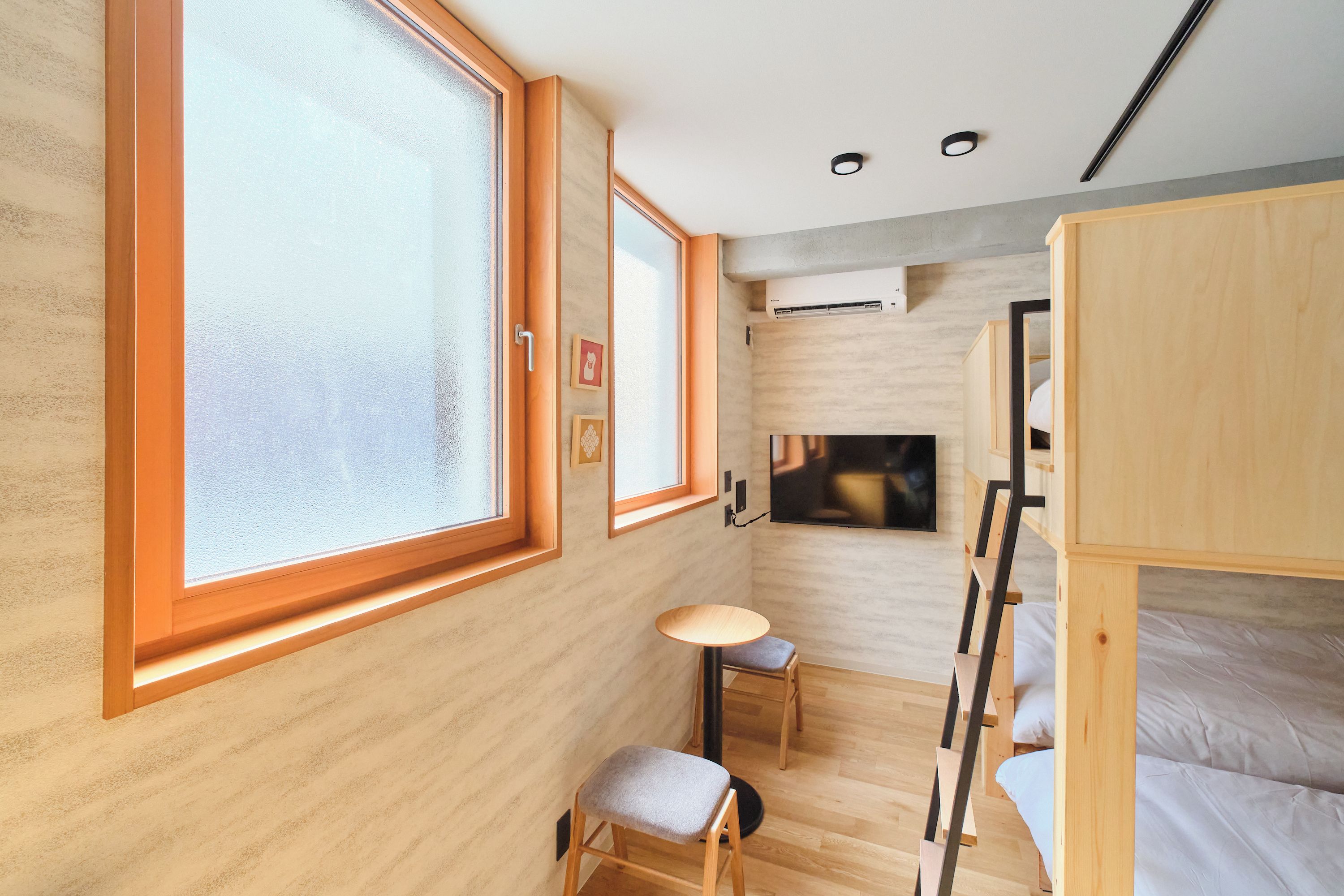 A modern, compact room with bunk beds, a small table, and a TV.