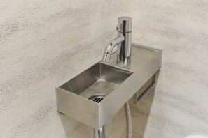 A stainless steel bathroom sink with a single-handle faucet and a flexible hose. - Tomori (Shinjuku-ku)
