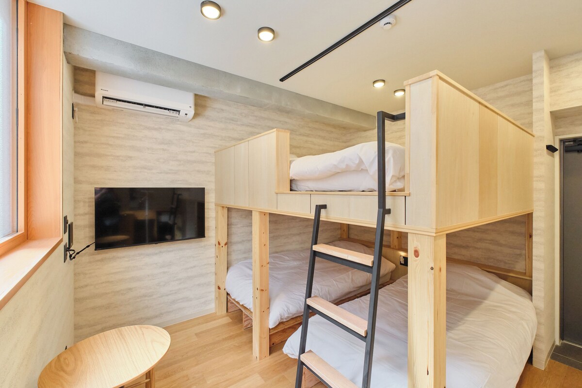 A bunk bed room with a TV, a desk, and a ladder.