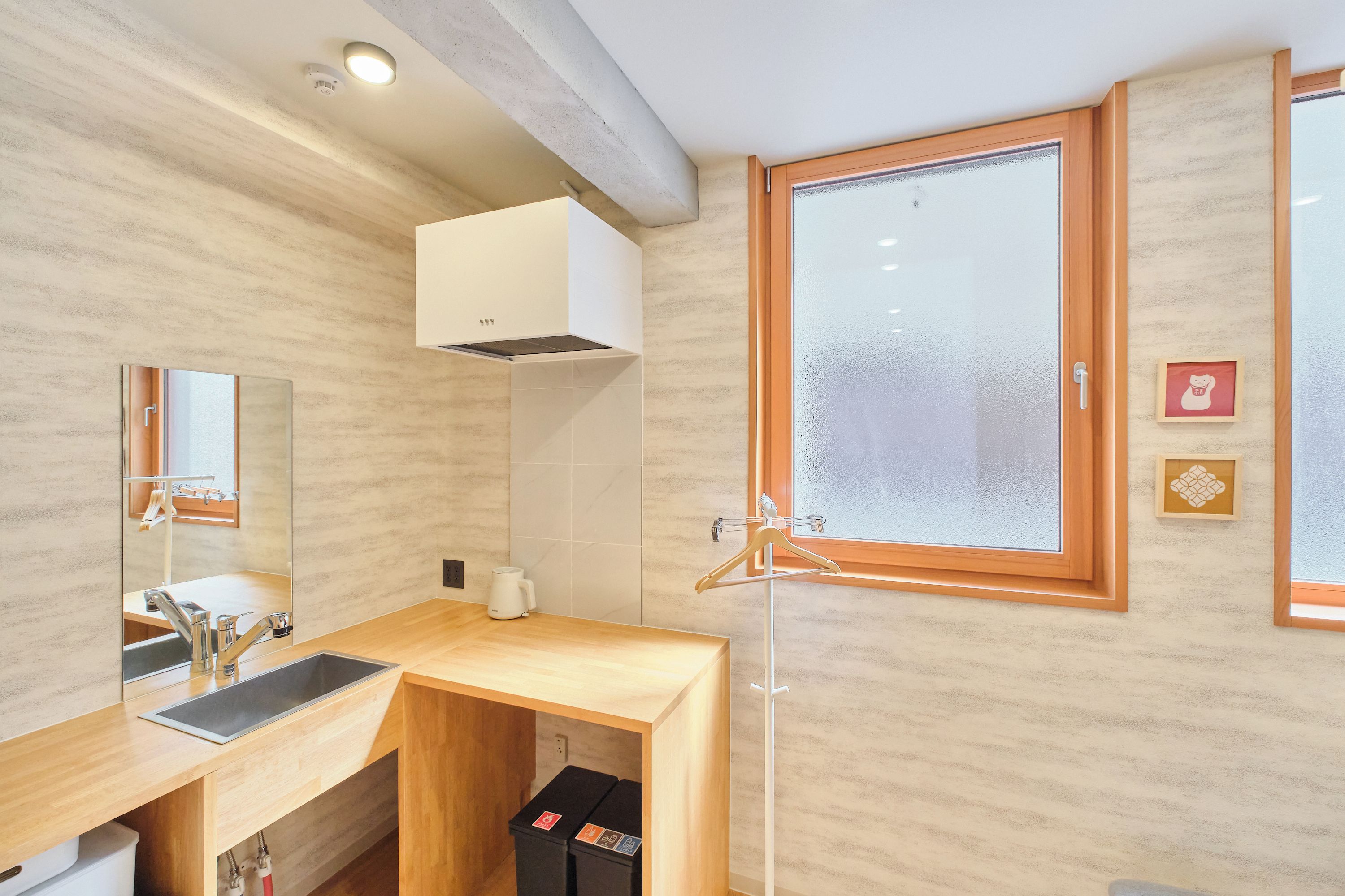 A modern bathroom with a wooden vanity, a sink, a mirror, and a window.