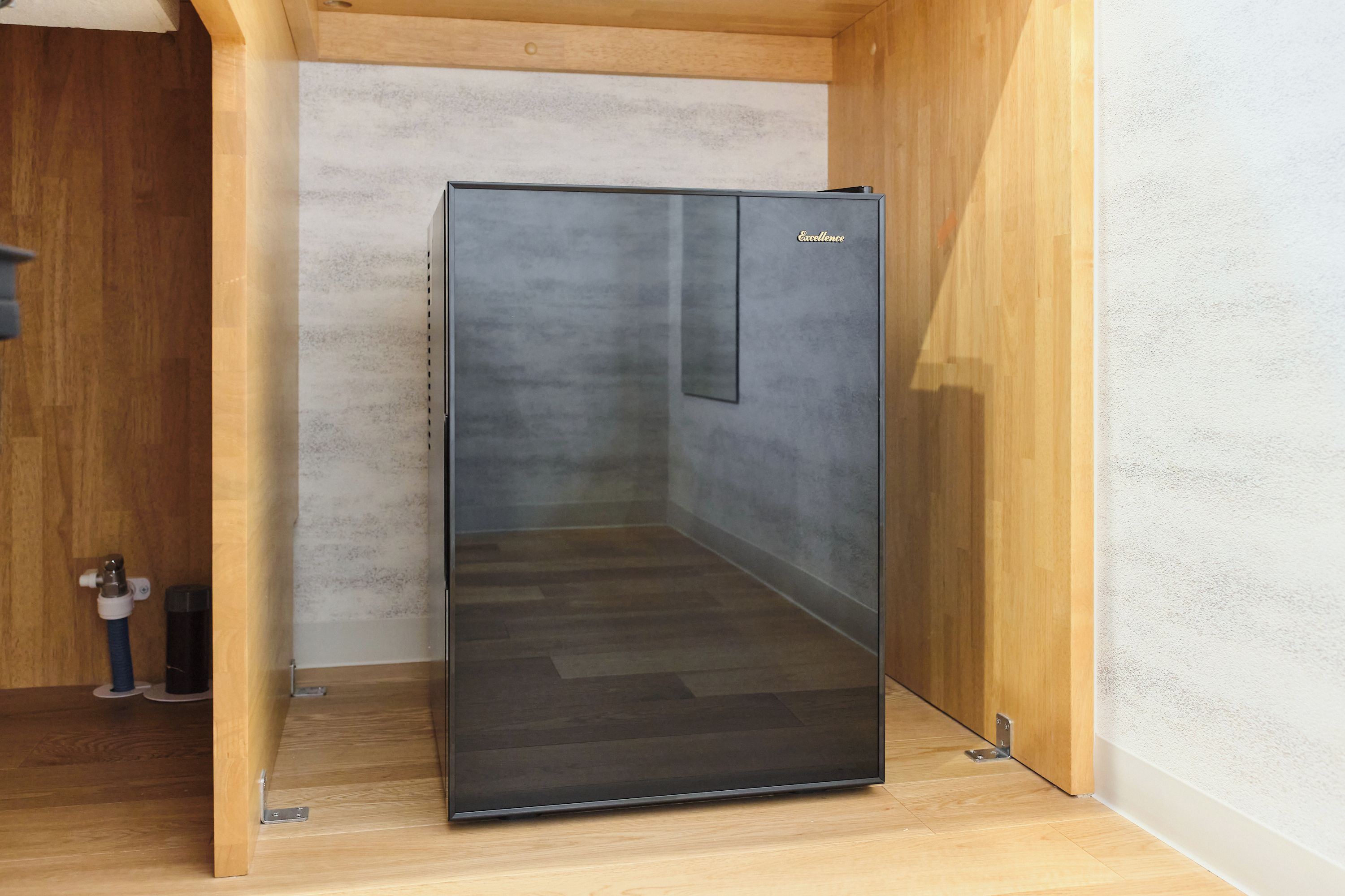 A modern, minimalist room with a built-in, dark-colored, glass-fronted cabinet.