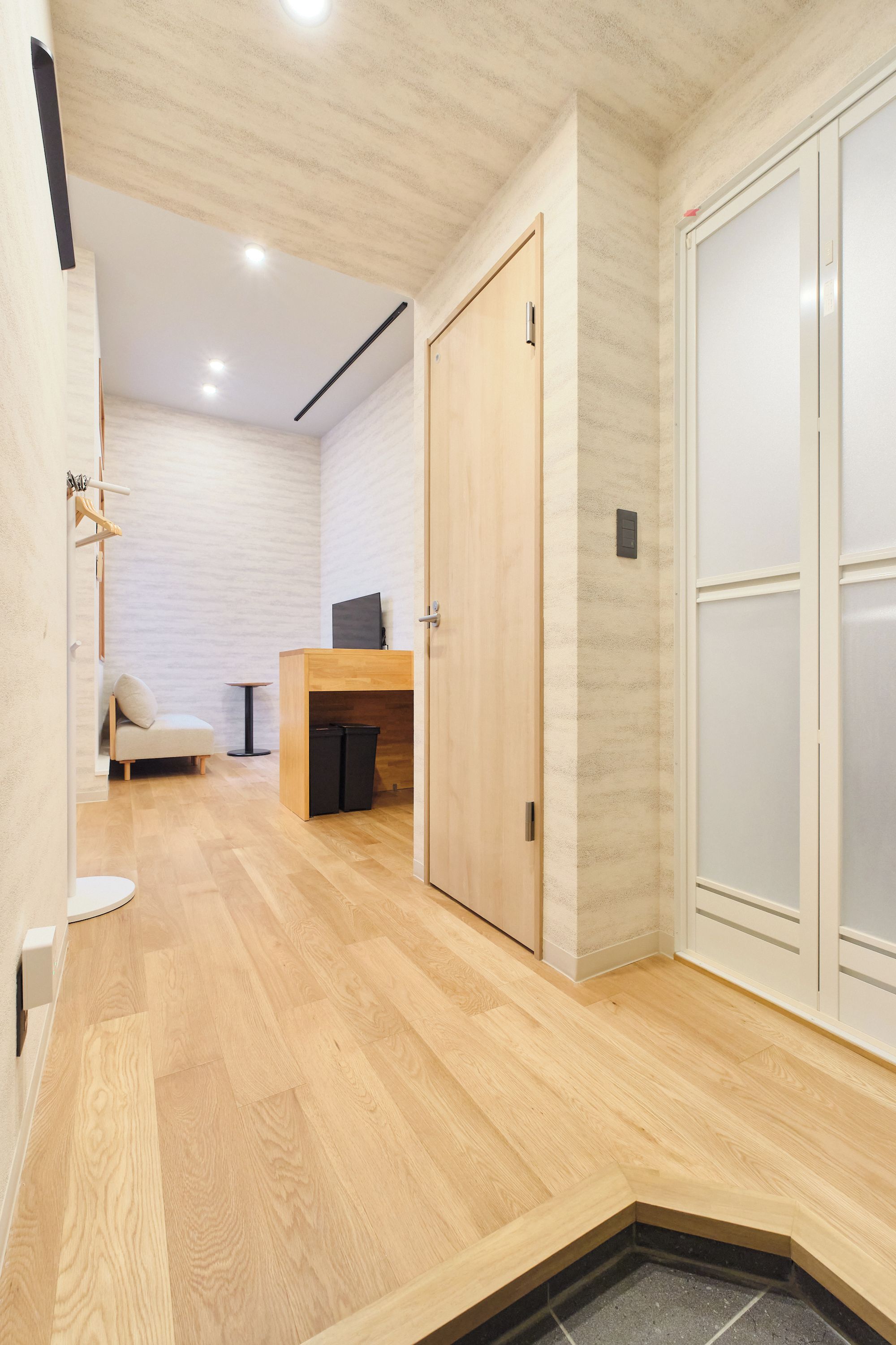 A hallway with wooden flooring, a desk with a chair, and a wardrobe.